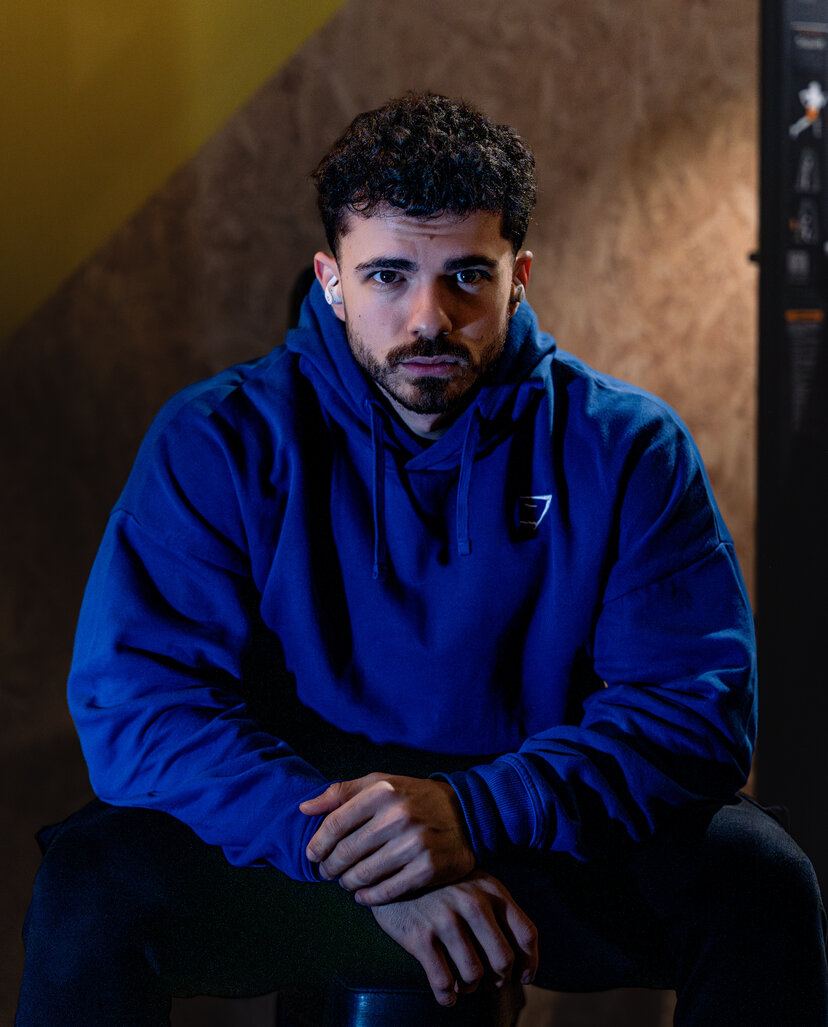Bogdan Calinescu in a blue hoodie, seated, hands clasped, direct gaze to camera